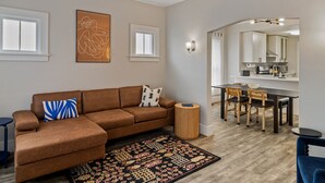 A modern living room with a brown sectional sofa, a patterned rug, and a dining area with a table and chairs. - 3 BLK Walk to Funky DT Ferndale's Restaurants & Bars/20 Min Drive to DT Detroit (Ferndale)
