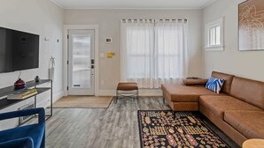 A living room with a sofa, a television, a coffee table, a rug, and a door leading to another room. - 3 BLK Walk to Funky DT Ferndale's Restaurants & Bars/20 Min Drive to DT Detroit (Ferndale)