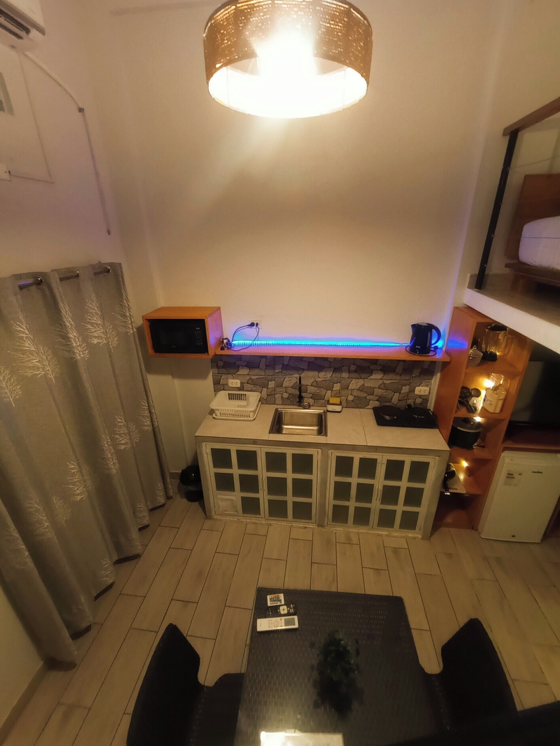 A compact kitchen with a built-in refrigerator, a sink, and a countertop with a kettle.