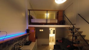 A compact apartment with a kitchenette, a dining area, a small bathroom, and a loft bedroom with a bed. - La Quinta Loft Apartments (Iquitos)