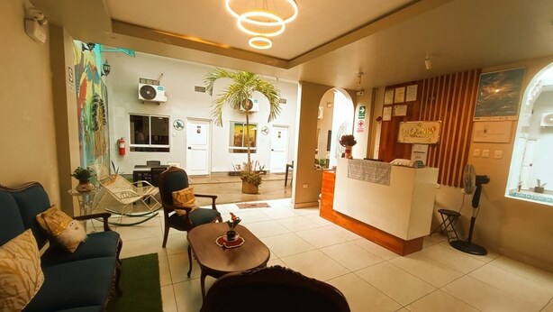 A hotel lobby with a reception desk, seating area, and a dining space. - La Quinta Loft Apartments (Iquitos)