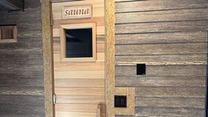 Puinen ovi, jossa on ikkuna ja nimikyltti, jossa lukee ”Sauna”.