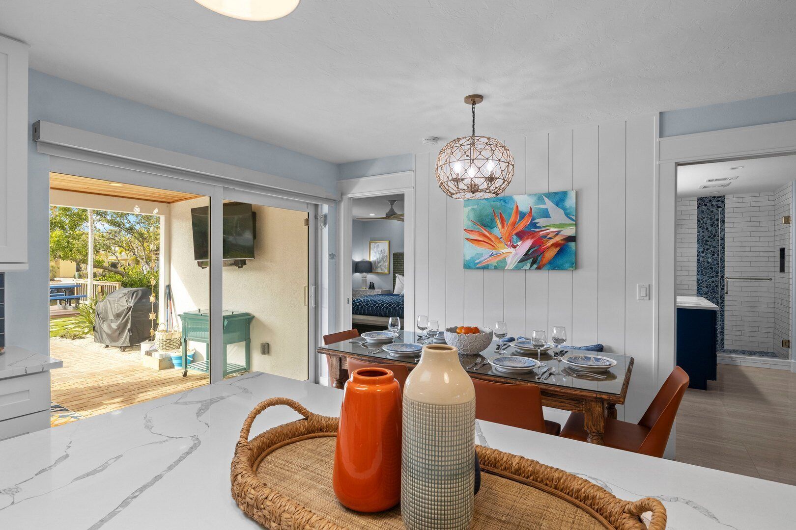 A modern dining area with a marble countertop, a woven placemat, and a large vase.