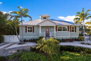 A single-story house with a gabled roof, a front porch, and a small attached garage. - Surfs Up: 2 Blocks to Beach! Private Pool & Spa! by Anna Maria Life Vacation Rentals (Holmes Beach)