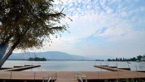 A wooden dock extending into calm water with a clear sky and distant mountains. - Osoyoos Lakeside 2 BDRM Condo! (Osoyoos)