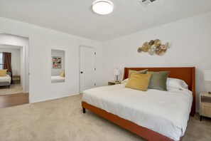 Ein Schlafzimmer mit einem großen Bett, einem Nachttisch, einem Spiegel und einer Tür.