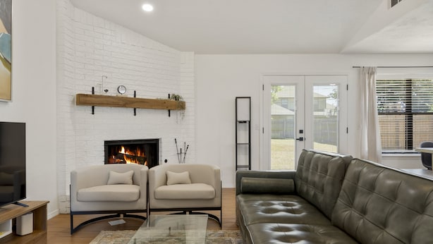 Una sala de estar con chimenea, dos sofás, una mesa de centro de vidrio y un televisor.