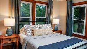 A bedroom with a bed, two bedside tables, two lamps, and a window with curtains. - Alice Rocks- Pet Friendly, Firepit, WiFi (Frenchburg)