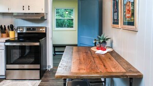 A compact kitchen with a built-in oven, a wooden dining table, and a blue door leading to a balcony. - Alice Rocks- Pet Friendly, Firepit, WiFi (Frenchburg)