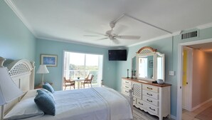 A bedroom with a bed, a ceiling fan, a dresser, a mirror, and a TV. - CP 326 Ocean View Condo- Welcome to Paradise (Fort Pierce)