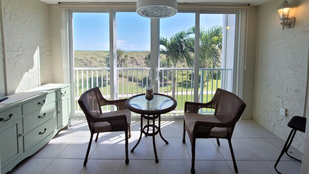 A balcony with wicker chairs, a glass table, and a view of the beach. - CP 326 Ocean View Condo- Welcome to Paradise (Fort Pierce)