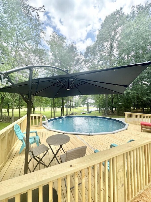 Eine Holzterrasse mit Whirlpool, Tisch und Stühlen.