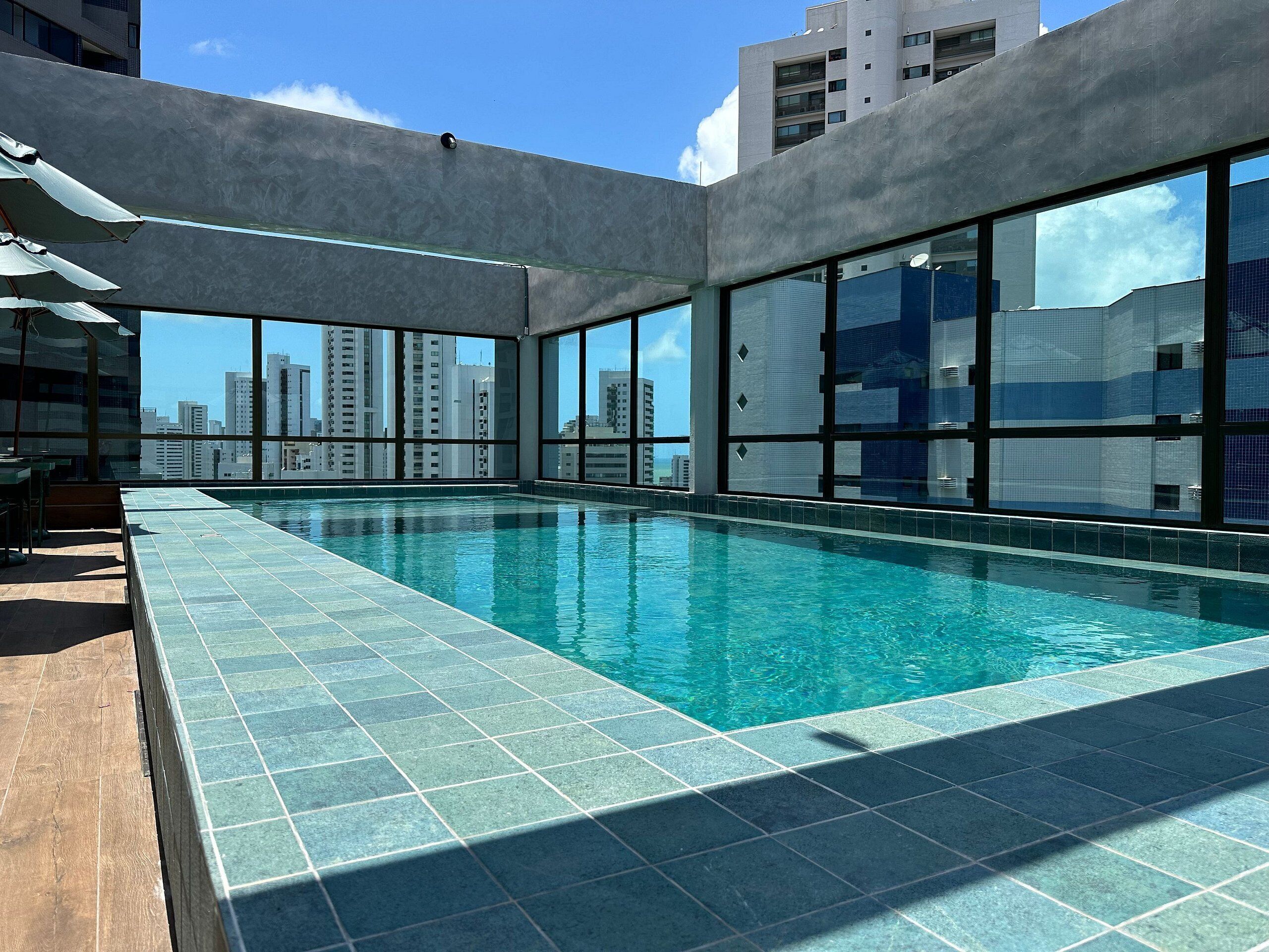 A rooftop swimming pool with a city view, large windows, and a modern design.