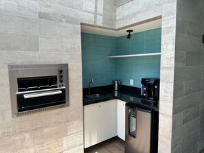 A compact kitchen with a built-in oven, a coffee maker, and a dishwasher. - APARTAMENTO ALTO LUXO (Recife)