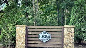 A wooden gate with a stone wall and a sign that reads "RETTREAT WATERS EDGE". - Sparks Fly / The Retreat at Water's Edge / 2 Kayaks, 1 Canoe, 1 Paddle Board (Tracy City)