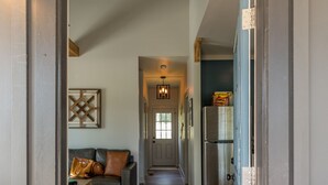 A hallway leading to a living area with a sofa, a rug, and a refrigerator. - Sparks Fly / The Retreat at Water's Edge / 2 Kayaks, 1 Canoe, 1 Paddle Board (Tracy City)