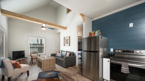 A modern kitchen with a stainless steel refrigerator, oven, and microwave. There is a dining area with a wooden table and chairs. - Sparks Fly / The Retreat at Water's Edge / 2 Kayaks, 1 Canoe, 1 Paddle Board (Tracy City)
