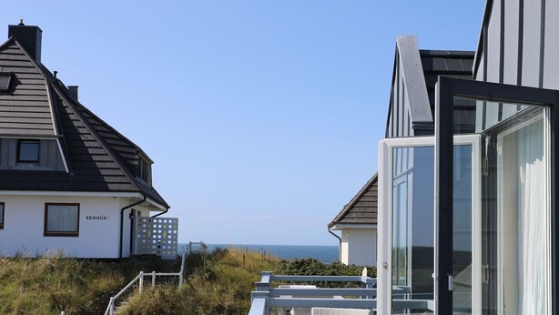 Un bâtiment situé sur la côte, offrant une vue dégagée sur la mer, avec une façade blanche et un design moderne.