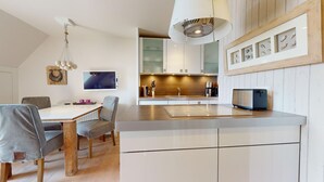 Une cuisine moderne avec des meubles blancs, un îlot central et un luminaire suspendu.