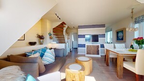 Ein modernes Wohnzimmer mit Sofa, Couchtisch und Essbereich mit Tisch und Stühlen.