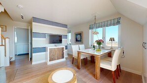 Eine moderne Küche mit Fernseher, ein Essbereich mit Tisch und Stühlen sowie ein großes Fenster mit Blick.