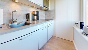 Eine moderne Küche mit Spüle aus Edelstahl, einer Kaffeemaschine und einem Toaster.