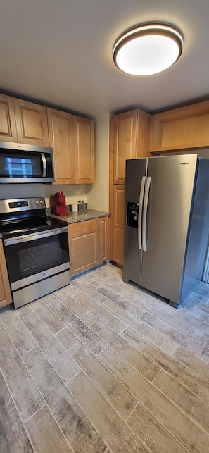 Una cocina con armarios de madera, un refrigerador de acero inoxidable, un microondas y un horno.