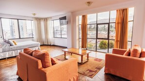 Una sala de estar moderna con un sofá, una mesa de centro y un ventanal con cortinas.