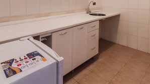 Una cocina con armarios blancos, un lavamanos y un refrigerador.
