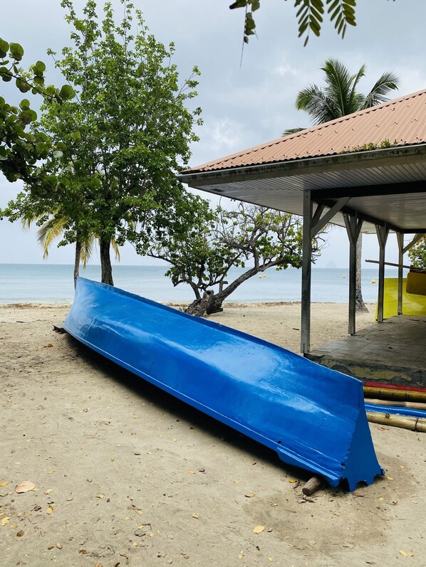 A beach with a blue slide, a covered area, and a view of the ocean.