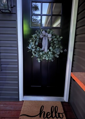 A black door with a wreath and a striped bow, a doormat with 'hello' written on it, and a window above the door. - Lake house on the point with beautiful lake views!  (Centralia)