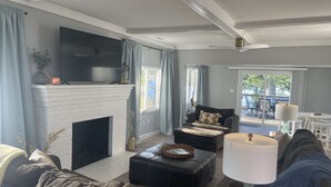 Una sala de estar con chimenea, televisor y comedor con mobiliario exterior.