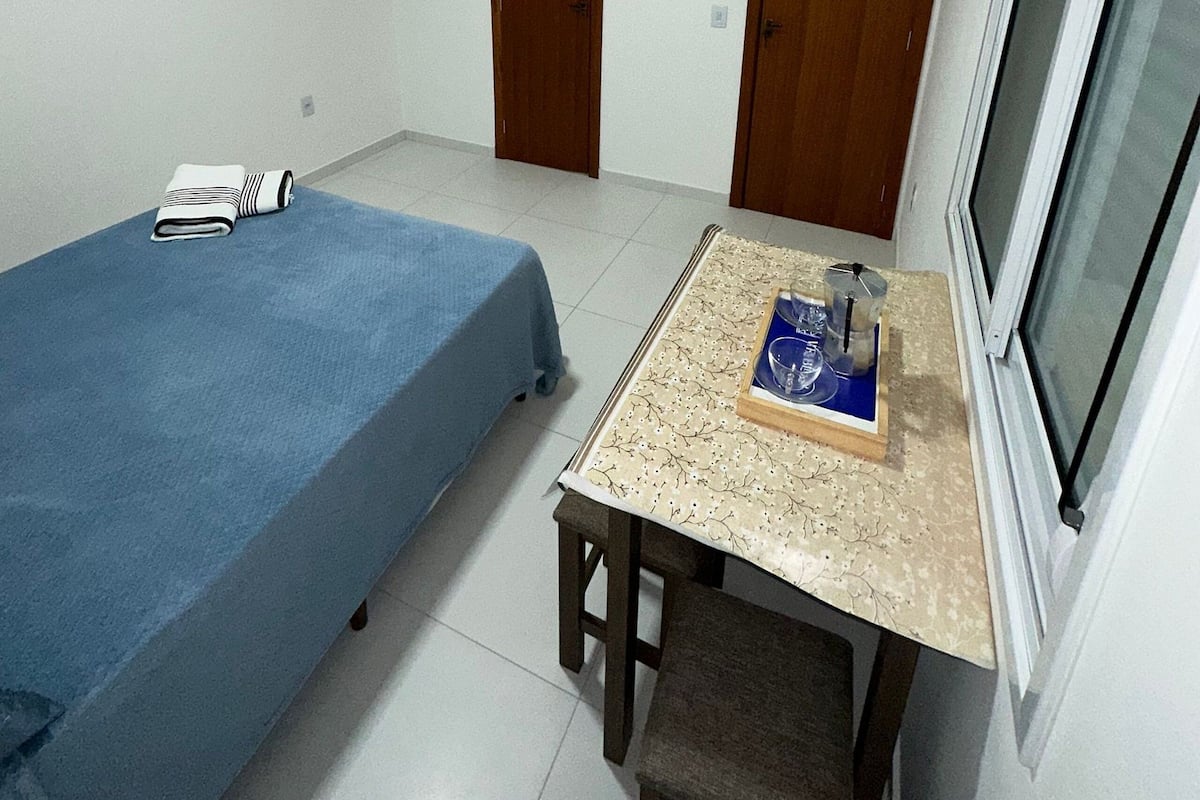 Une petite pièce propre, avec un lit, un bureau et une fenêtre.
