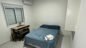 Een kleine, schone kamer met een bed, een bureau en een raam.