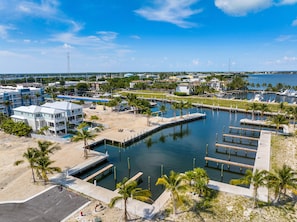 Un port de plaisance doté de quais, d’une piscine et d’une plage bordée de palmiers.