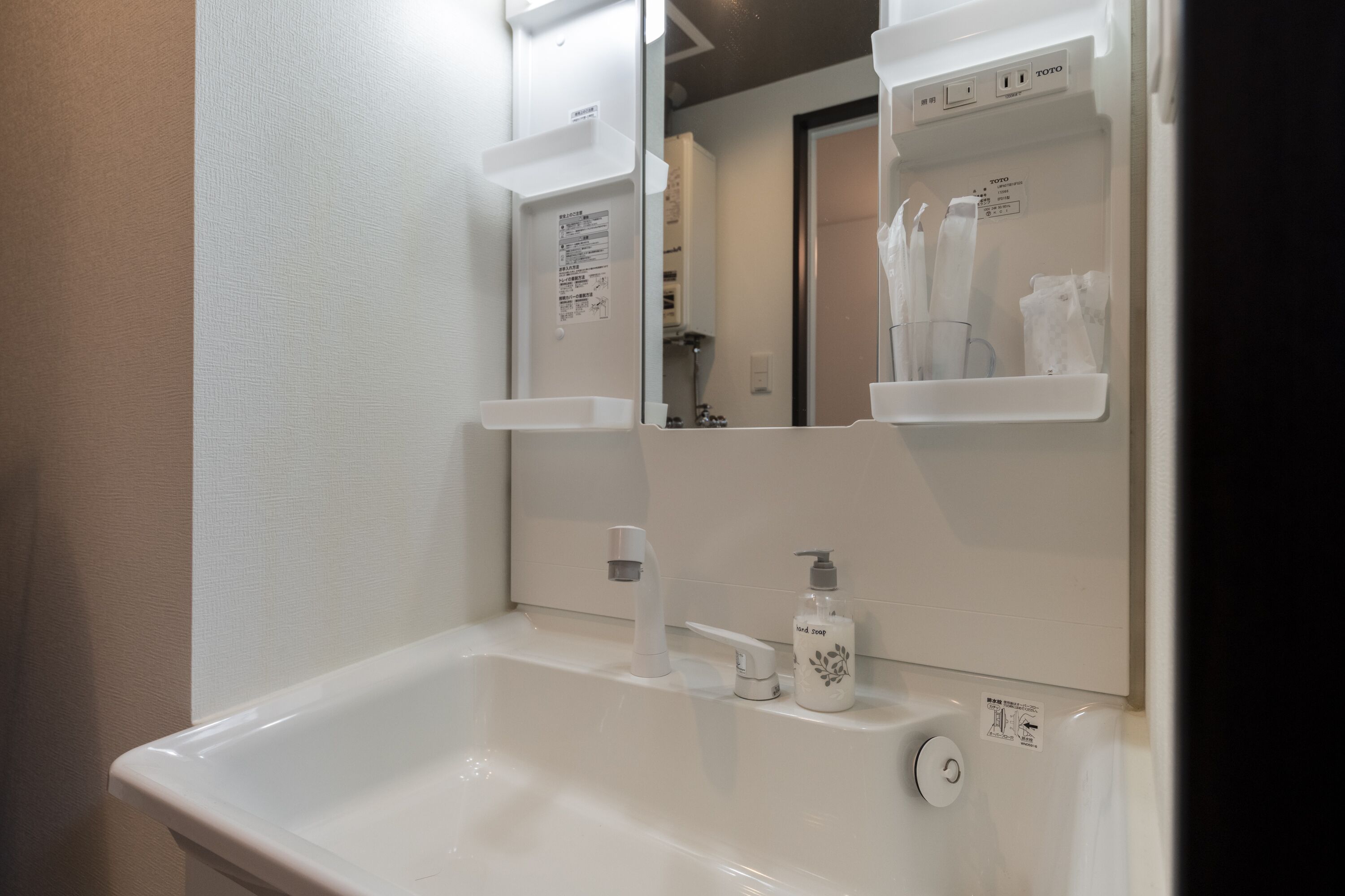 A bathroom with a white sink, a mirror, and a shelf with toiletries.