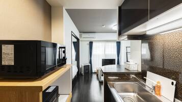 Una cocina compacta equipada con microondas, fregadero y un refrigerador pequeño.