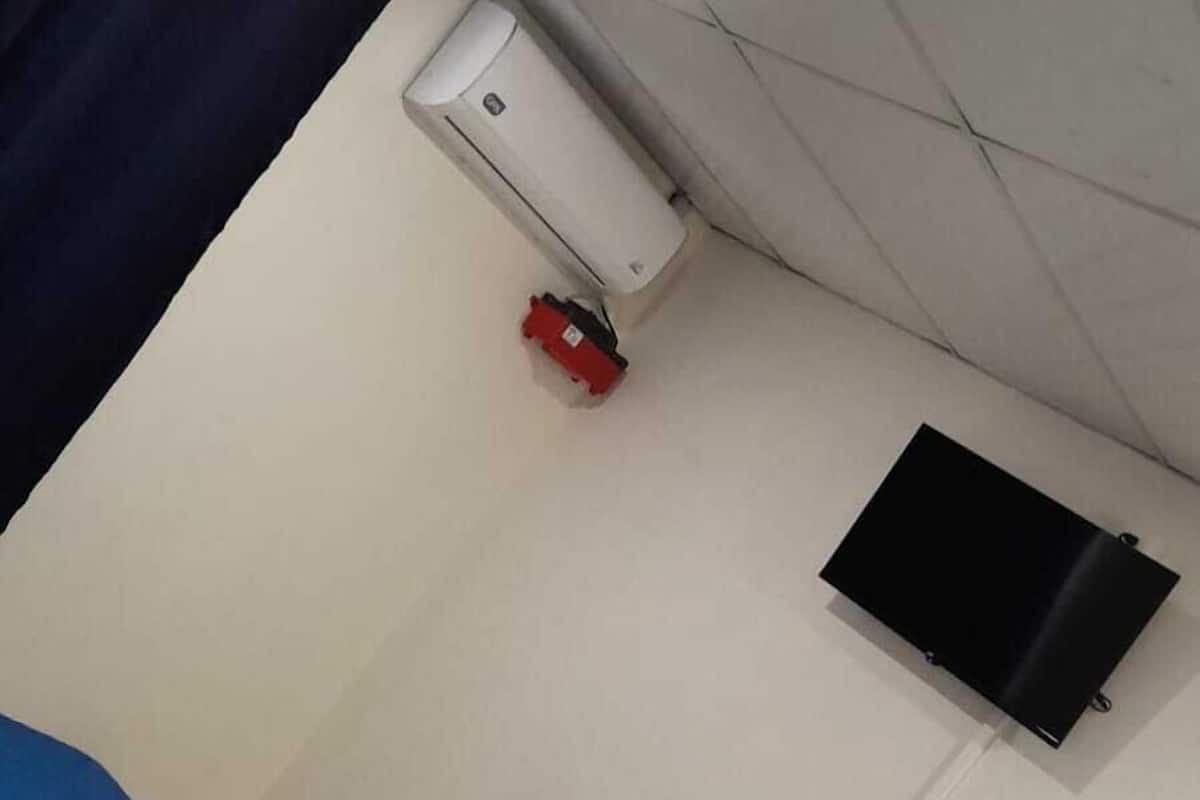 Ein Zimmer mit einem Bett, einem flachbildfernseher an der Wand, einer Klimaanlage und einer Steckdose.