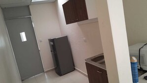 A compact kitchen with a refrigerator, a sink, and a cabinet. - THE HEROES HOUSE (San Salvador)