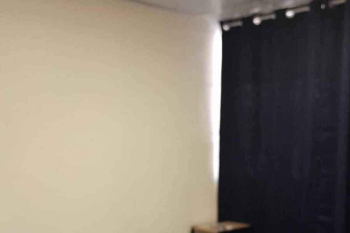 Ein Schlafzimmer mit einem Bett, einem Nachttisch und einem Fenster mit Vorhängen.