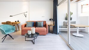 Ein modernes Wohnzimmer mit einer Couch, einem runden Couchtisch, einem Schreibtisch und einem Sessel.