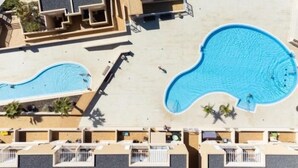 Een resort met meerdere zwembaden, een centrale binnenplaats en een reeks verbonden gebouwen met balkons.