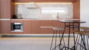 Uma cozinha moderna com micro-ondas embutido, forno de aço inoxidável, pia e uma mesa redonda com banquetas.