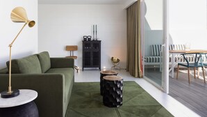 Uma sala de estar moderna com um sofá verde, um armário preto e um espaço de refeições com mesa e cadeiras.