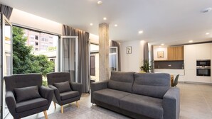 A modern living room with a grey sofa, two armchairs, and a large window with curtains. - ★ New · Guimera Family Suites - A (Santa Cruz de Tenerife)