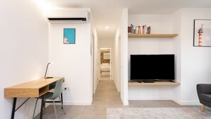 A modern living room with a flat-screen TV, a wooden desk, a chair, and a bookshelf. - ★ New · Guimera Family Suites - A (Santa Cruz de Tenerife)