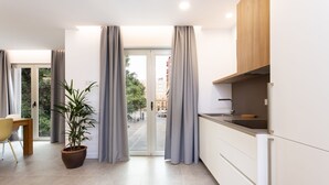 A modern kitchen with a dining area, a potted plant, and a view through the glass door. - ★ New · Guimera Family Suites - A (Santa Cruz de Tenerife)