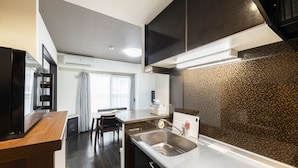 A modern kitchen with a stainless steel sink, a wooden countertop, and a black backsplash. - Essence (Sapporo)