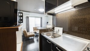 A modern kitchen with a built-in stove, a sink, and a dining area with a table and chairs. - Estrella (Sapporo)