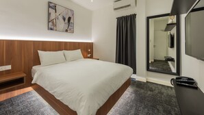 Une chambre d’hôtel moderne dotée d’un grand lit, d’une table de chevet, d’un téléviseur à écran plat et d’un miroir.